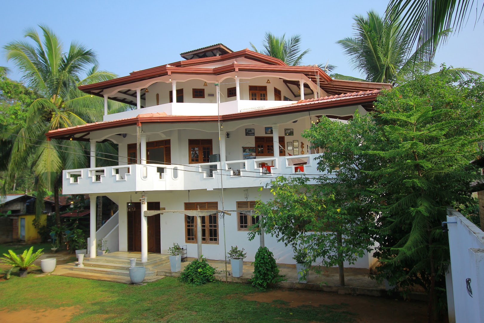 White multi level villa surrounded by coconut palms and garden trees